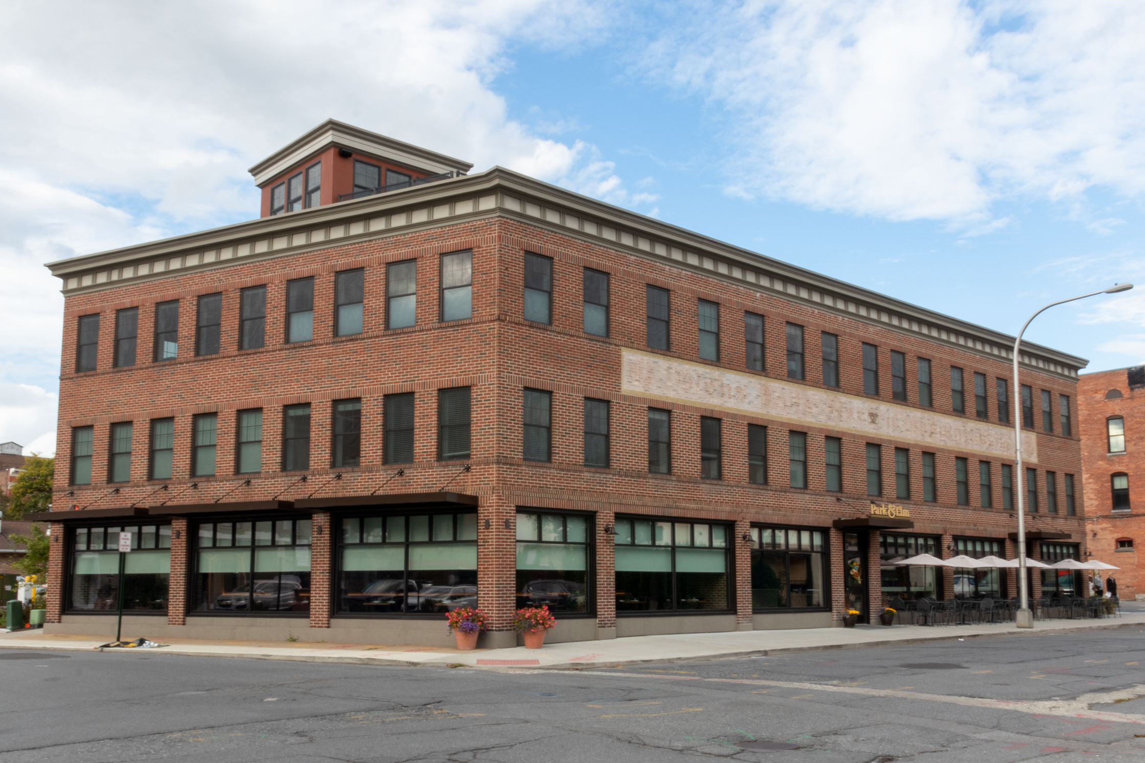 The newly renovated historic Park and Elm building in Glens Falls, New York by AJA Architecture and Planning. It includes a new cornice and elevator tower for roof access. The Elm Street side of the building has sun shad awnings to protect guests from the sun while dining. 