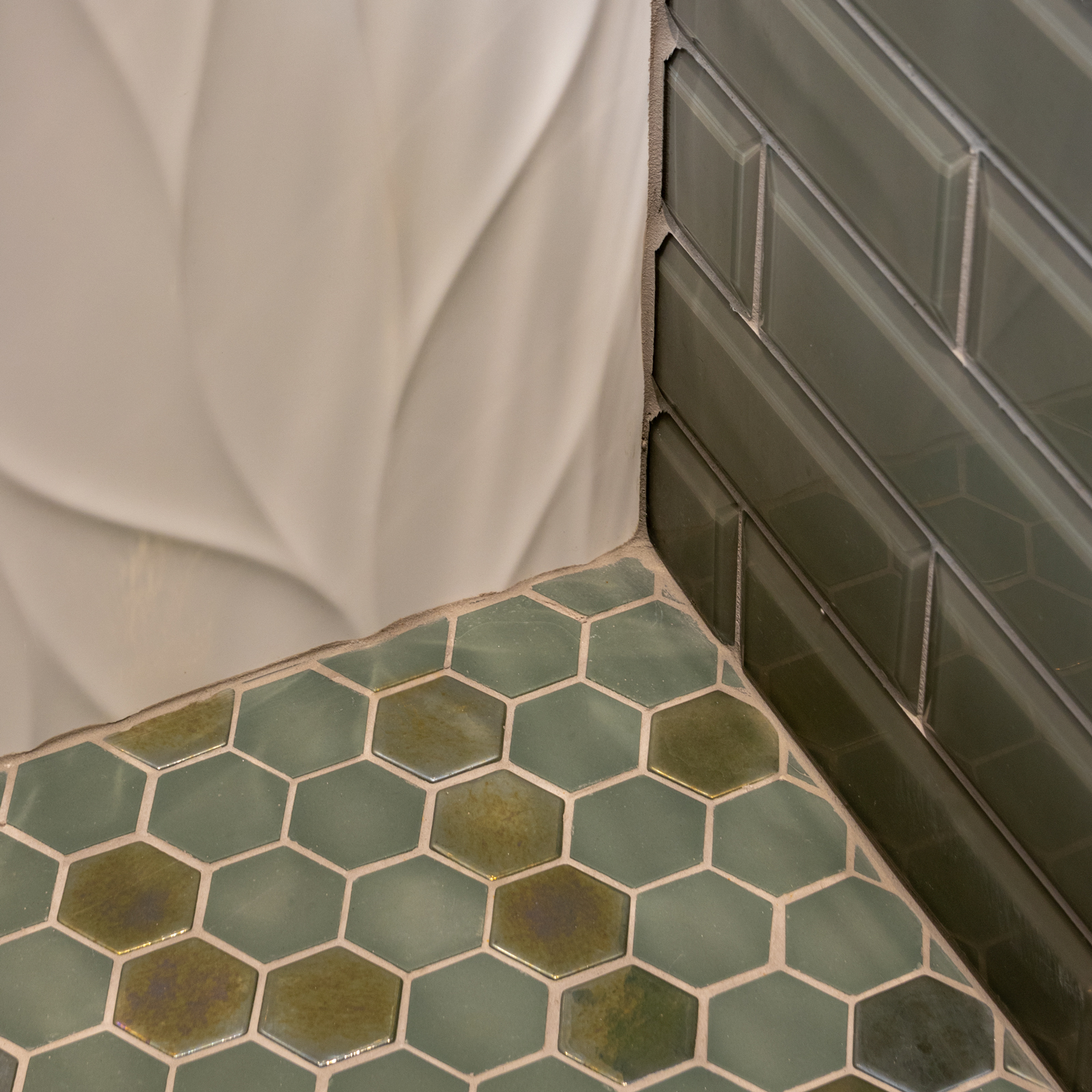 The first guest room shower has three tertiary tiles that all complement each other as parts of a monochromatic green color scheme.   