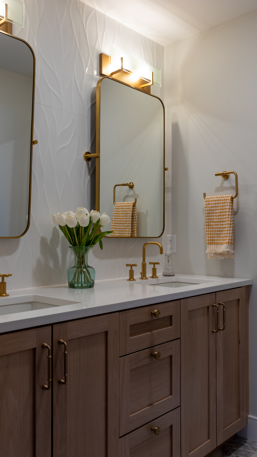 T White Oak Vanity is the feature of this bathroom. Designed with green tones in mind, this bathroom utilizes a leafy wave tile and a monochromatic color scheme to enchant guests with a spa feel. 