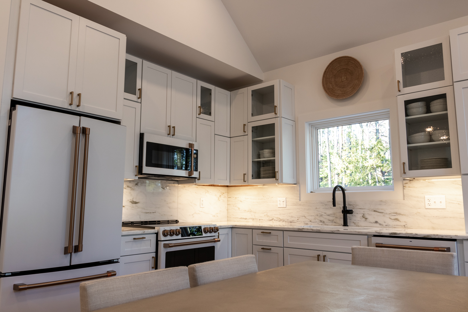 The Rock View Cabin kitchen is adorned with an elegant white interior that was inspired by historic lakeside camps. The white with bronze hardware Cafe Appliances gives a classy and refined look.   