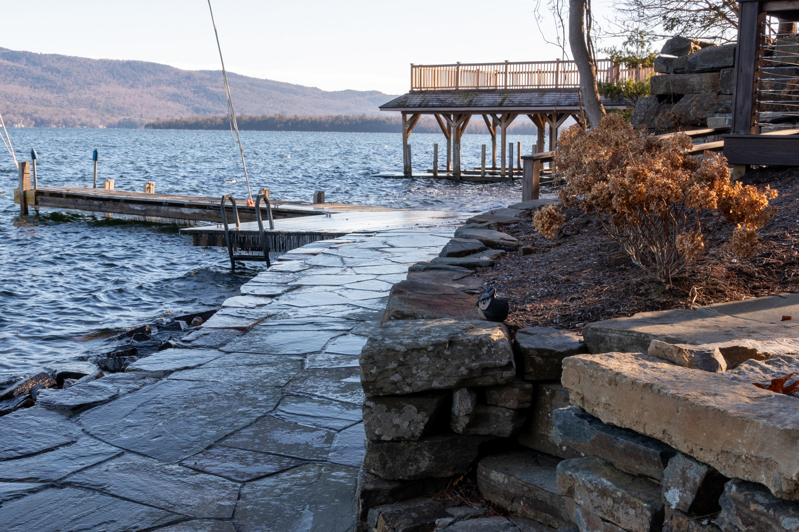 Views of beautiful Lake George from the carefully placed stone shoreline landing at the Rock View Residence designed by AJA Architecture and Planning. 